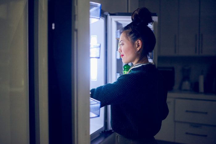 woman looking in refrigerator late at night