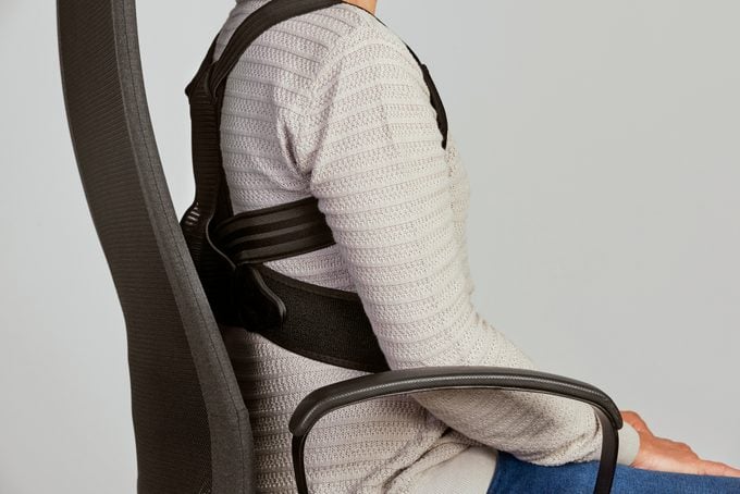woman wearing a posture corrector in desk chair