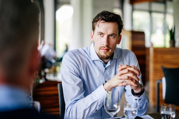 Businessman Listening To Colleagues Over Lunch At Restaurant Table