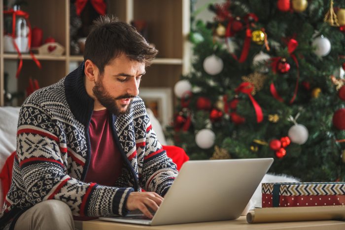 Young man using laptop in the living room near the Christmas tree