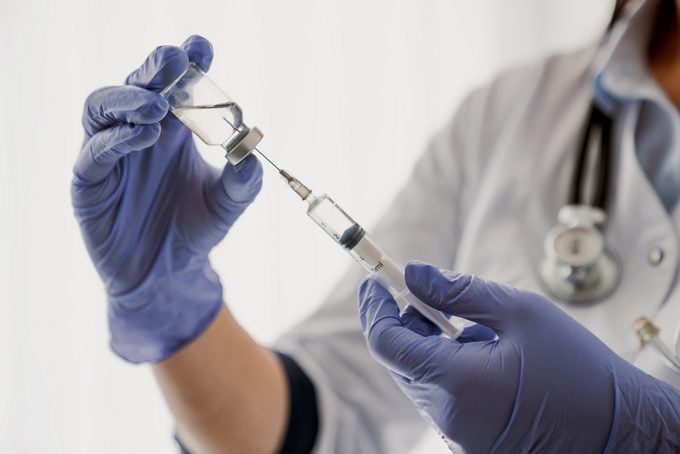 doctor holding flu vaccine vial and syringe