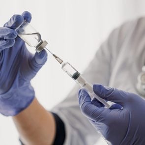 doctor holding flu vaccine vial and syringe