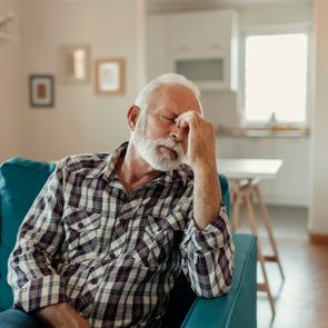 mature man with headache on couch at home