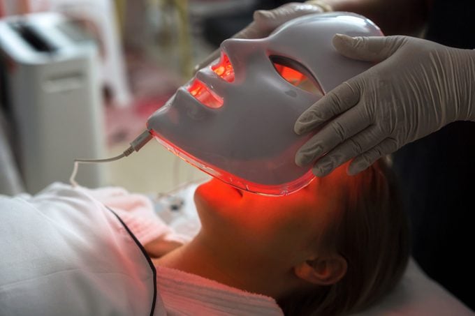 Woman getting LED mask regenerative treatment at the facial spa.