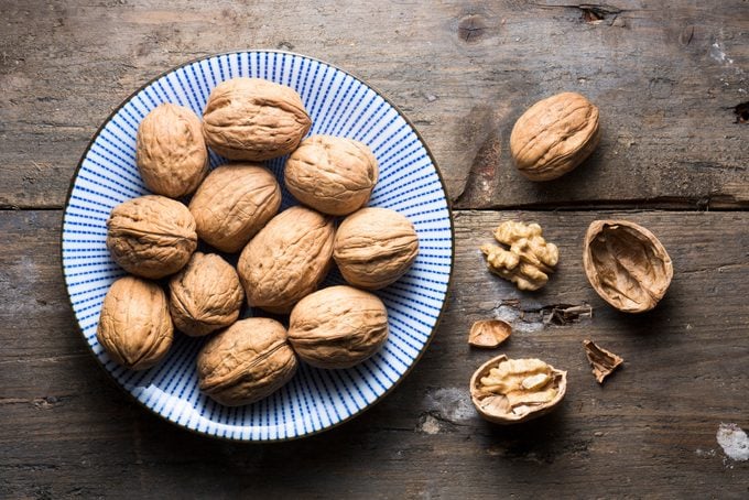 Overhead bowl of walnuts on a rough wooden background