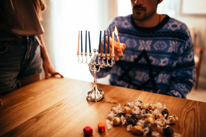 Young man lighting candlesticks on traditional jewish menorah for Hannukah