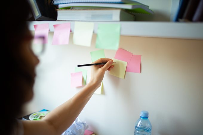 woman writing on post-it notes on the wall