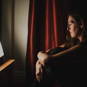 Profile of woman sitting looking at light therapy lamp in a dark room