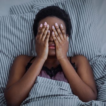 woman with closed eyes with hands in bed