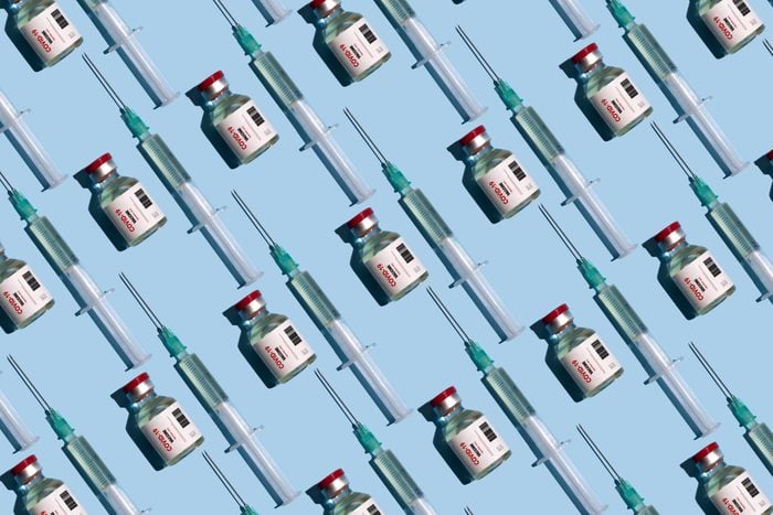 Repeated vials and syringes with covid-19 vaccine on the blue background