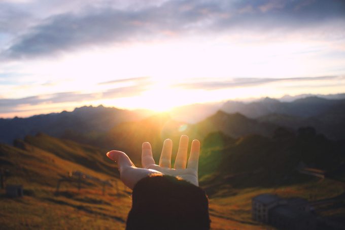 Hand Outstretched Towards Scenic View Of Mountains