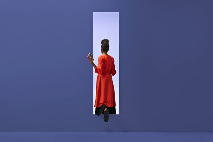 Woman walking into rectangular opening in colored wall