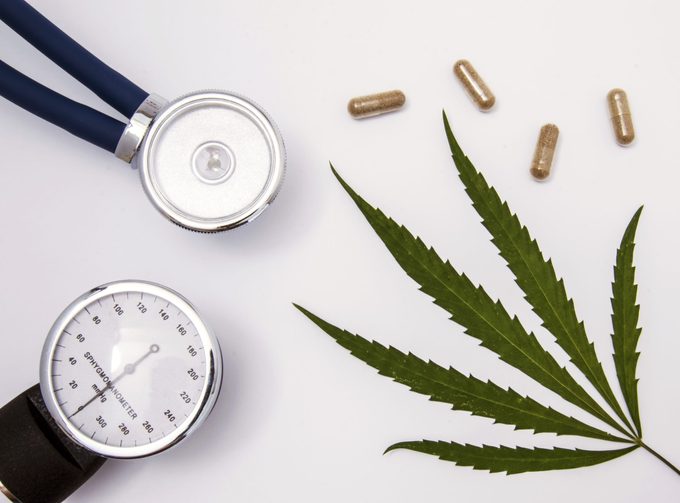 marijuana leaf and blood pressure monitor on white background