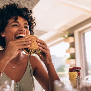 Woman enjoying eating burger at restaurant