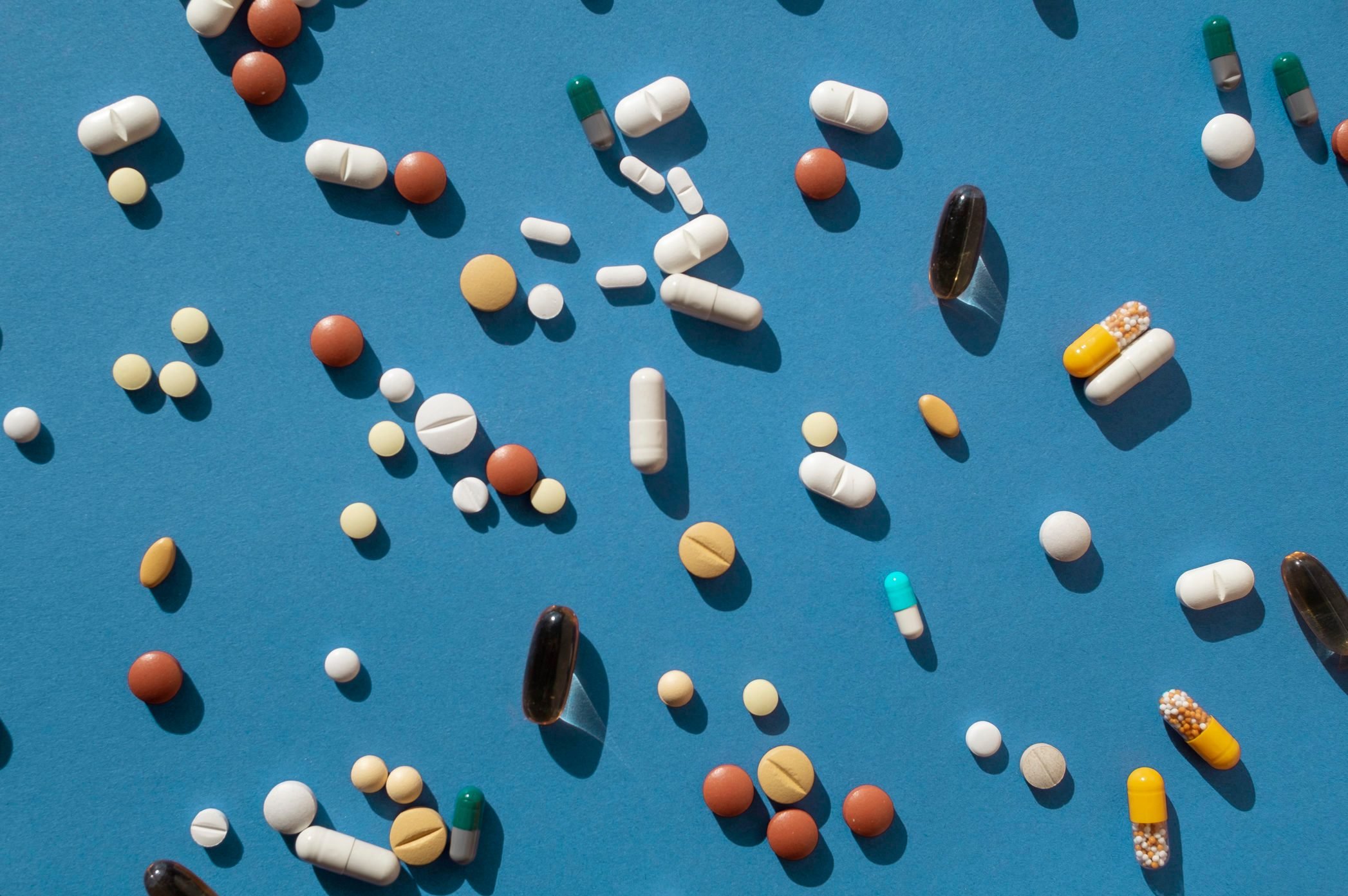Top view of various pills and tablets on the blue background