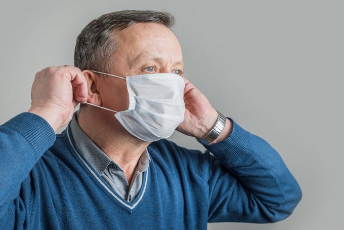 Adult man puts on surgical mask to protect against virus Covid 19. Prevention of Coronavirus.