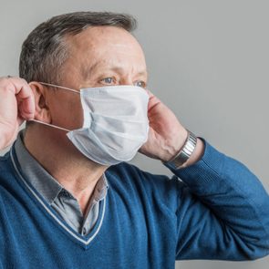 Adult man puts on surgical mask to protect against virus Covid 19. Prevention of Coronavirus.