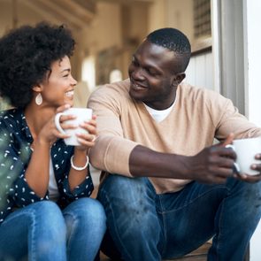 young couple talking and drinking coffee at home smiling