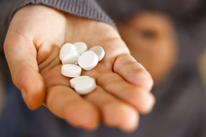 Treatment tablets. Close-up of a white pill in woman's fingers.