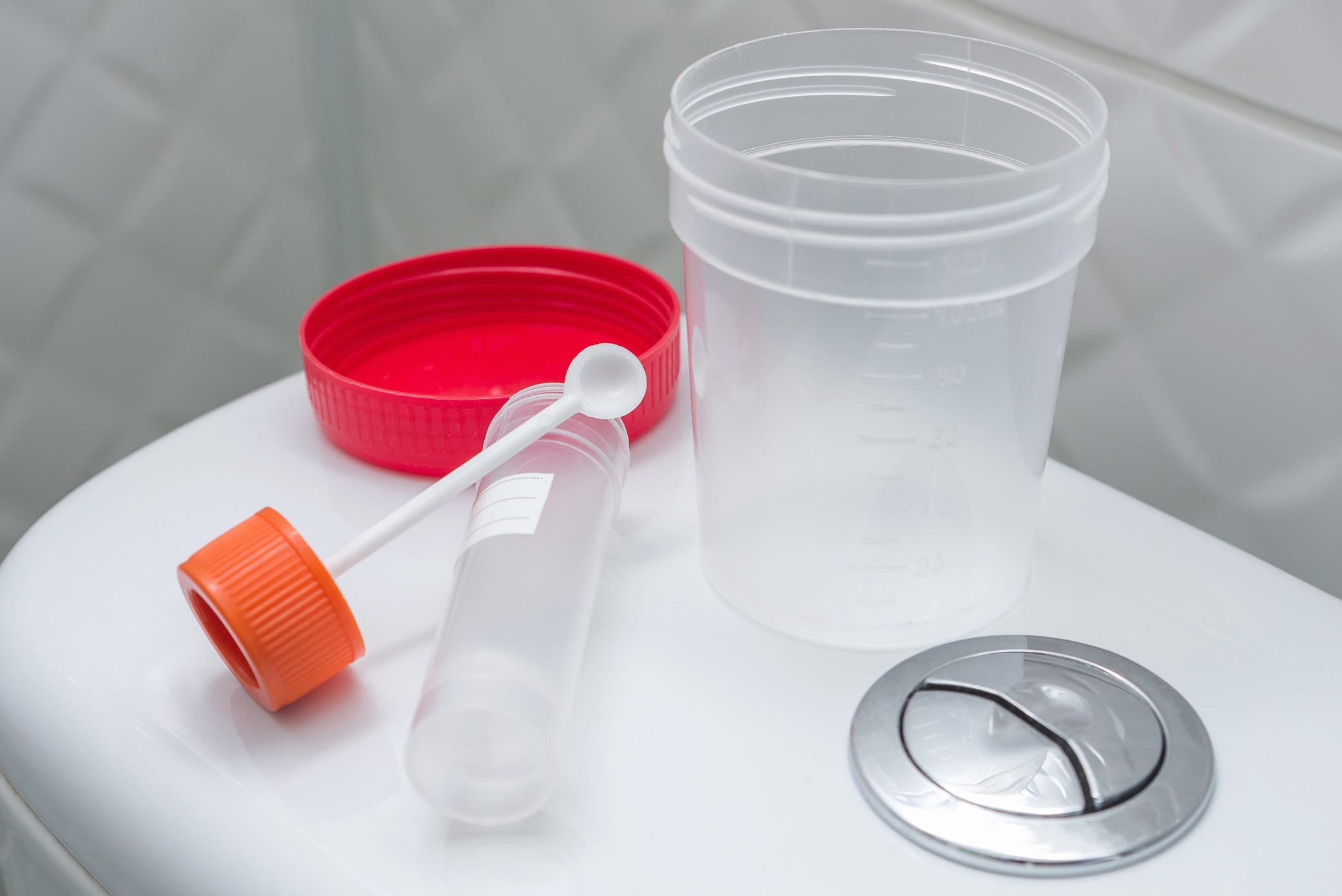 stool and urine sampling cups on back of toilet