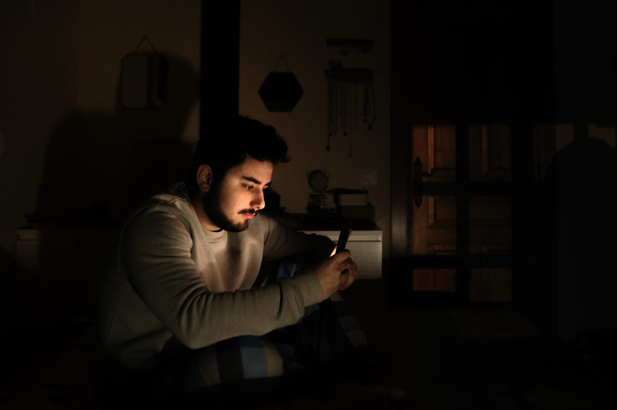 Jonge man in bed kijkend naar zijn smartphonescherm