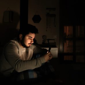 Young man in bed looking at his smartphone screen