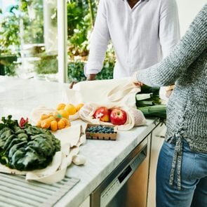 Couple organizing fresh organic vegetable and fruit on kitchen counter after shopping