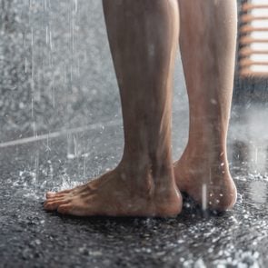 Legs of the girl standing under the shower under the stream of water, health beauty and hygiene concept