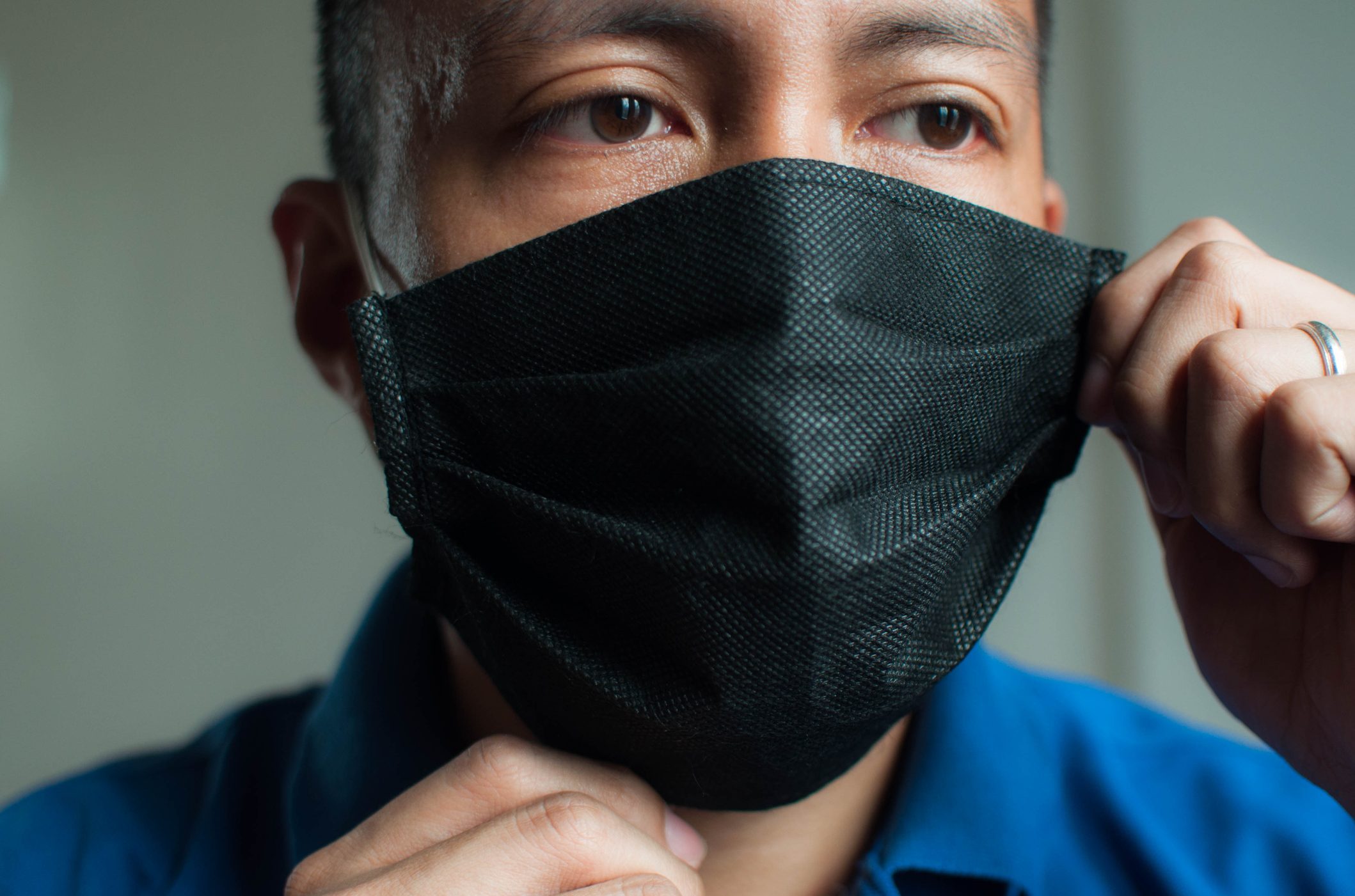 A young Southeast Asian man is wearing a black protective face mask during the "new normal" in coronavirus pandemic