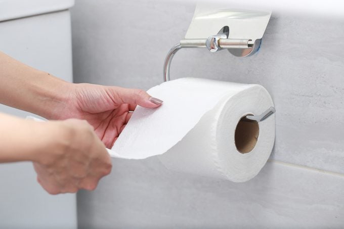 Cropped Hands Of Woman Holding Toilet Paper In Bathroom