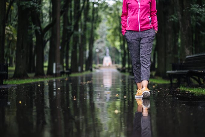 Carefree young woman enjoying relaxing walk after rain
