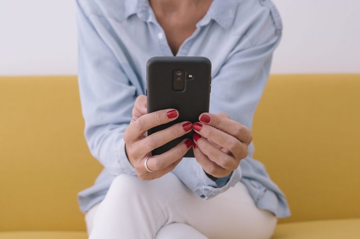 Midsection Of Woman Using Mobile Phone While Sitting On Sofa