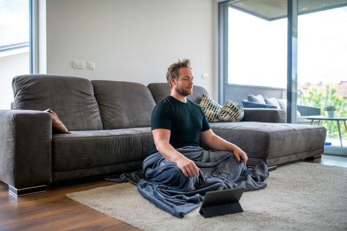 Caucasian Man Meditating Using Digital Tablet in the Living Room
