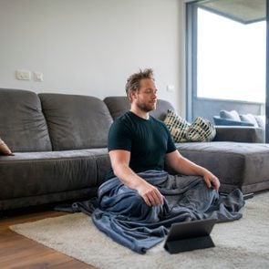 Caucasian Man Meditating Using Digital Tablet in the Living Room