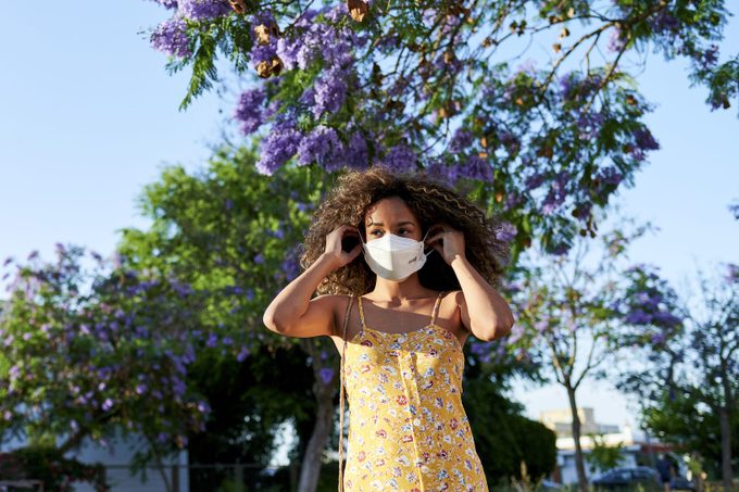 Woman outdoors putting on antiviral mask