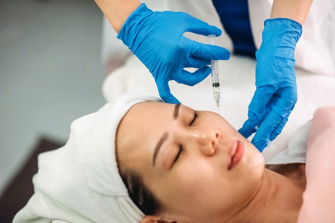 mujer recibiendo inyección en la cara en el salón de belleza facial
