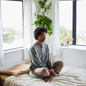 Young man sitting alone on his bed and meditating