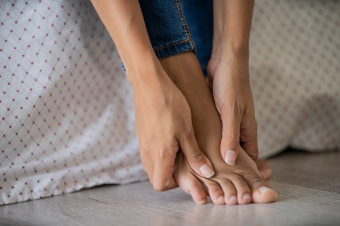 Low section of young woman massaging her foot