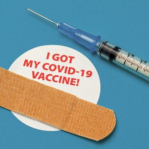 covid vaccine sticker and band aid on blue background