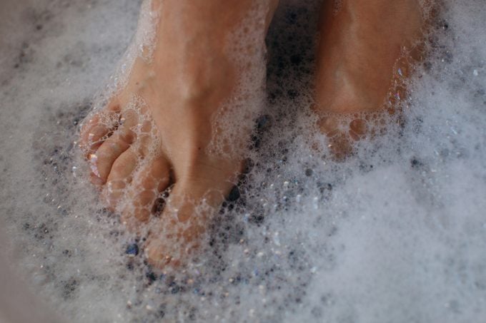 Close-up of a woman's feet covered in soap suds