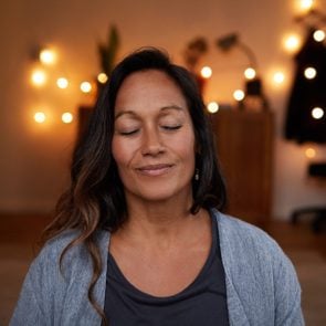 Serene mature woman smiling while meditating at home