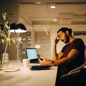 Exhausted businessman with head in hand working late at creative office