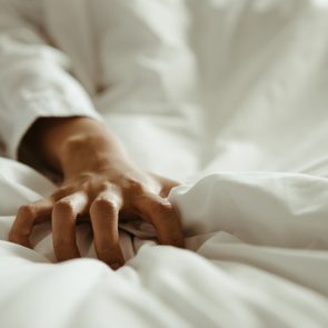 Close up hand of female pulling white sheets in ecstasy , feeling and emotion concept