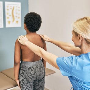 Osteopath examining spine to a male kid. Medical exam, scoliosis, kyphosis to a children