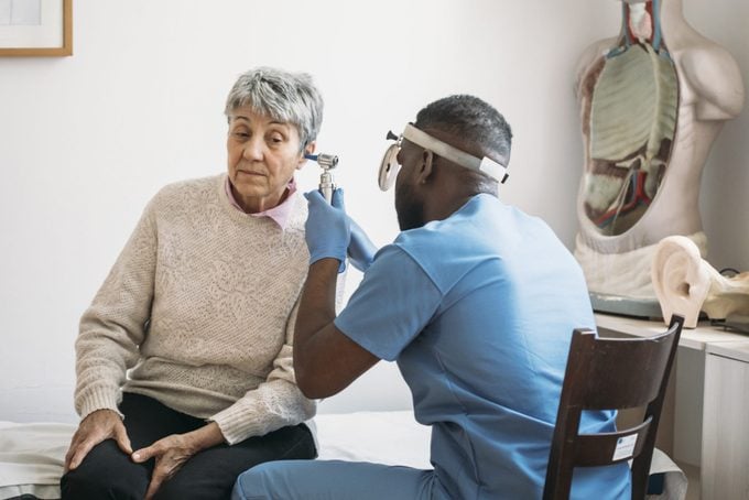 Mature adult woman has ears checked by doctor at routine medical appointment