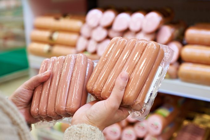 Woman chooses sausages in vacuum package at store