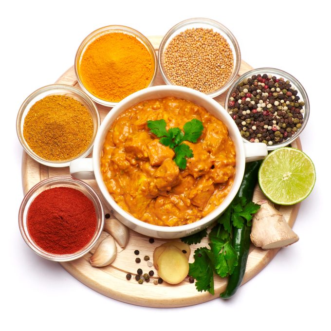 Plate Of Traditional Chicken Curry And Set Of Spices On White Background