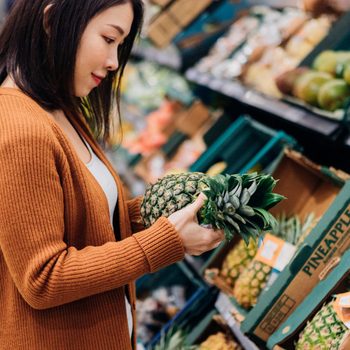 Young woman shopping for fruits and vegetables in grocery store
