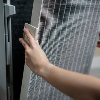 Woman hand open air purifier for clean dirty air purifier HEPA filter.