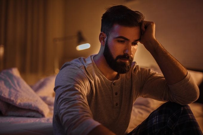 Depressed young man in his bedroom thinking about something